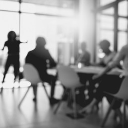 Out of focus black and white image of a team collaborating in a meeting room